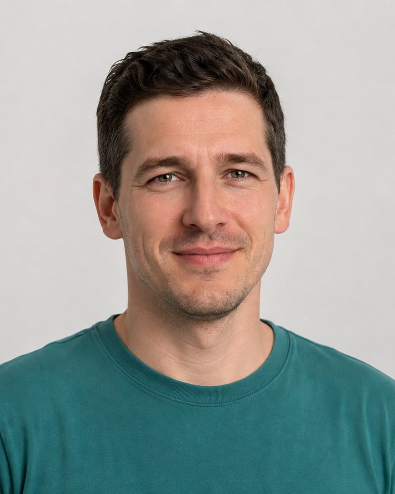Jonas Reinke, Saalleitung, im petrolfarbenen Shirt vor hellgrauem Hintergrund.